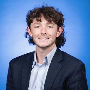 Headshot of Jack Thacker on a blue background
