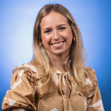 Headshot of Maggie Wall on a blue background