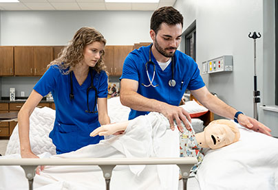 Two nursing students work in a lab setting.