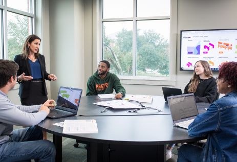 Teacher lecturing students in classroom, sitting at round table