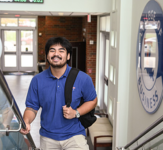 A student walking up the stairs in the College of Business