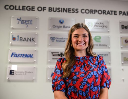 Female student standing in front of College of Business corporate partners