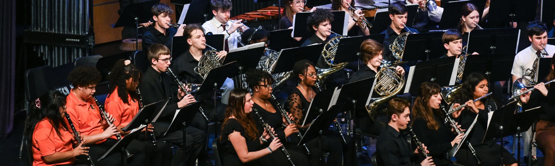a group of high school students playing musical instruments on a stage