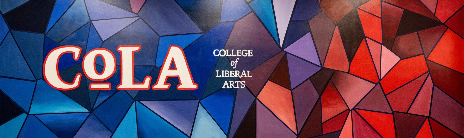 geometric red and blue mural with "COLA: College of Liberal Arts" painted on it 