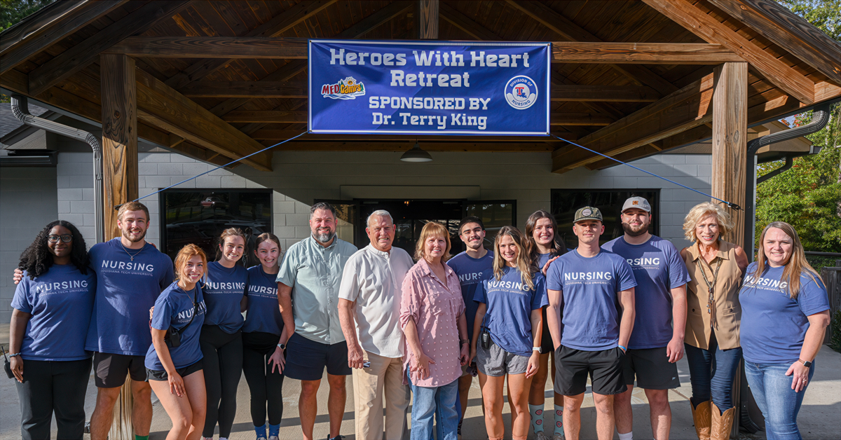 A group stands together under a "Heroes with Heart Retreat" banner