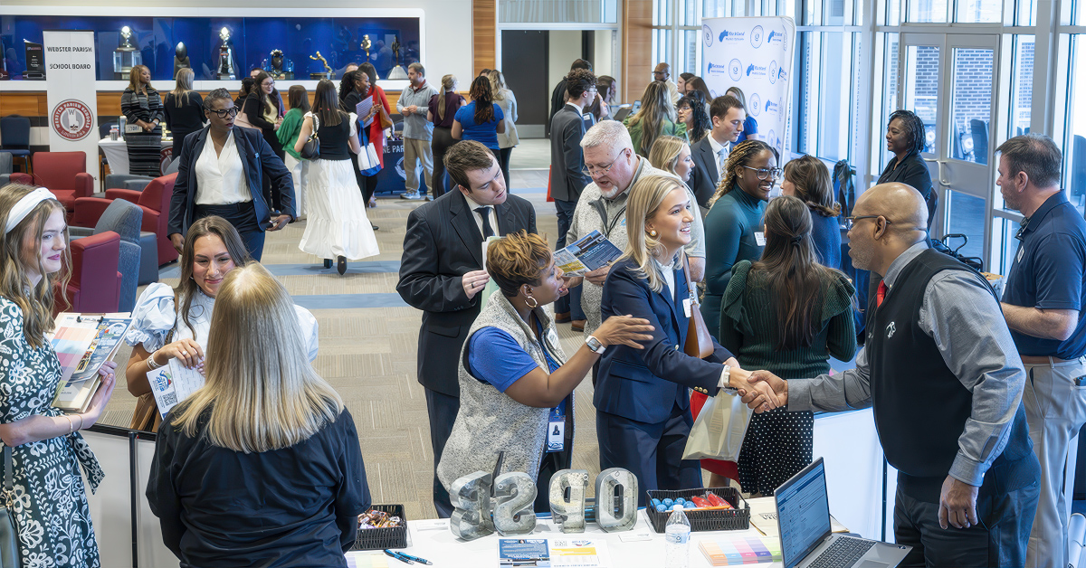 A student shakes hands with an employer at a recruitment event
