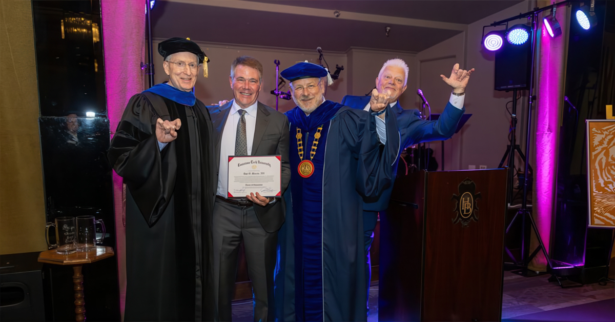 Men in caps and gowns present a degree