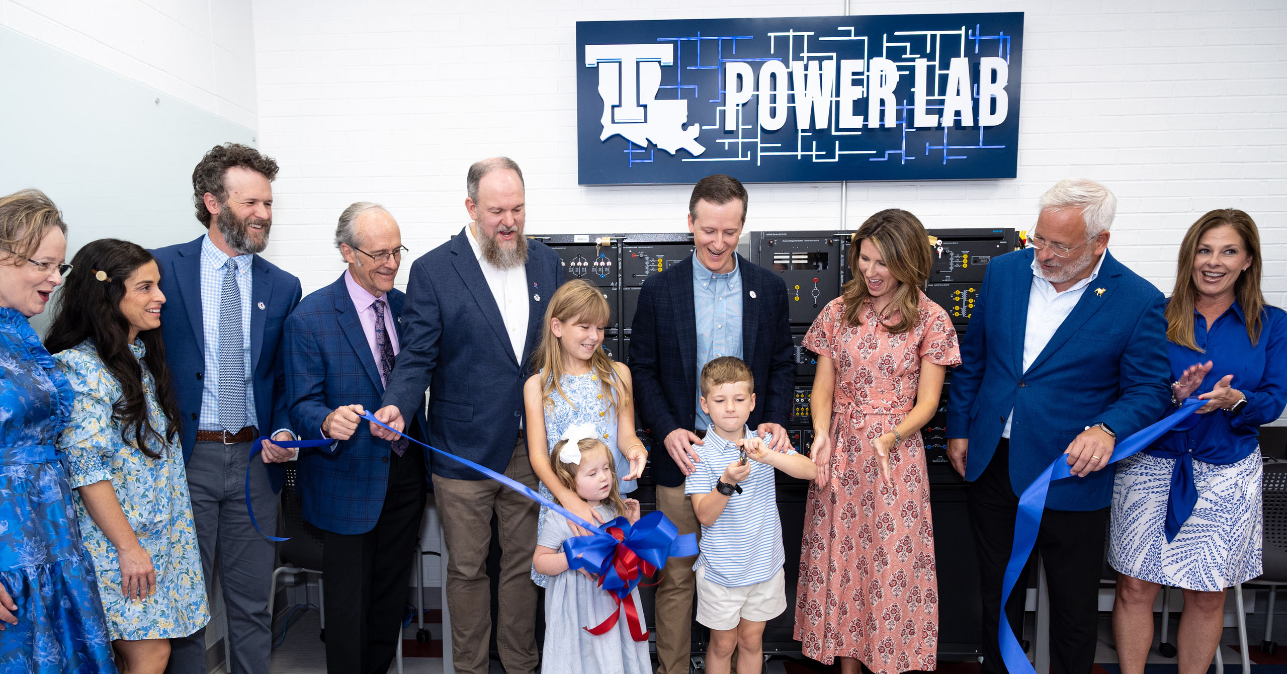 A group gathers to cut a blue ribbon at the Smoak Power Lab