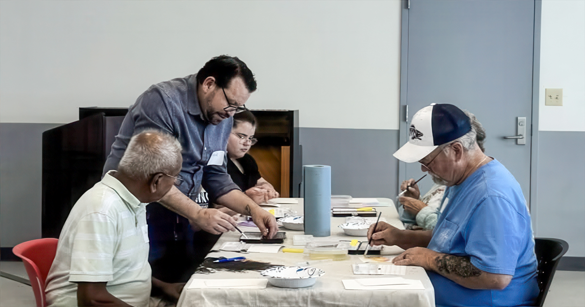 A man provides guidance to people at a table learning to watercolor