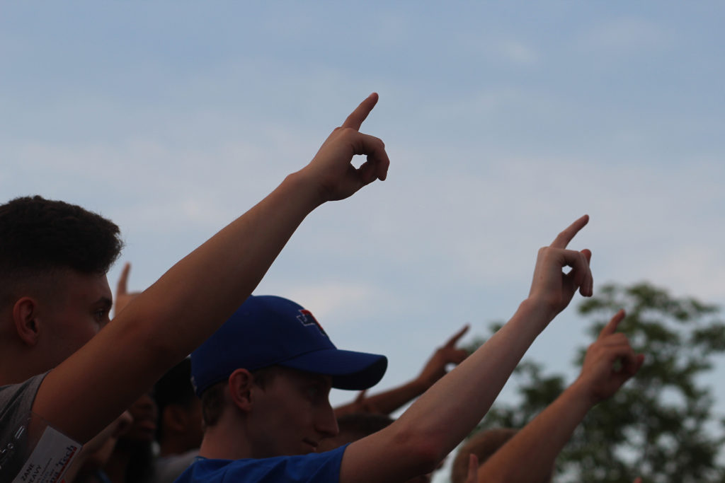 Students holding one finger in the air for Alma Mater