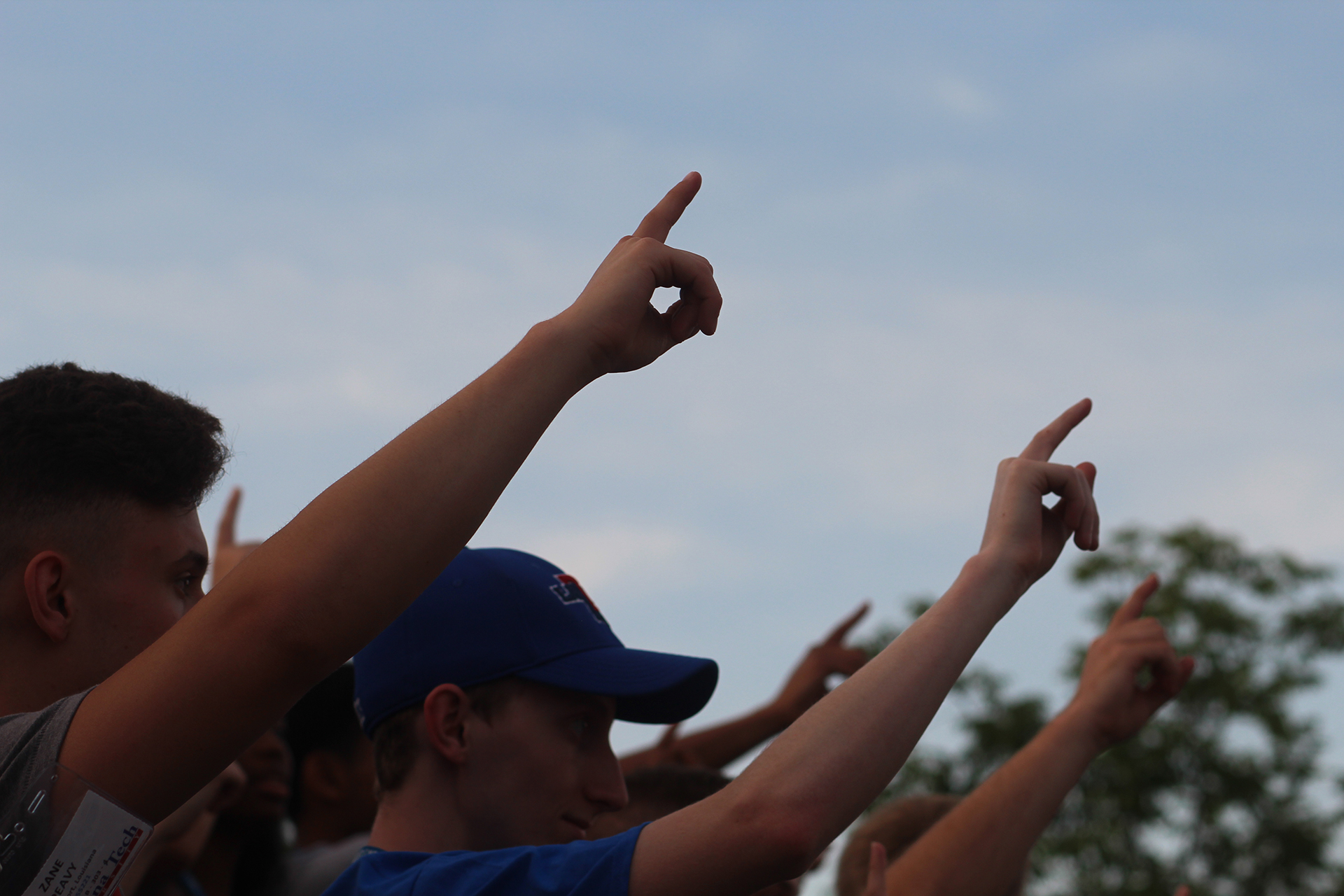 Alma Mater Students holding one finger in the air for Alma Mater