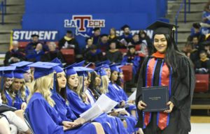 A winter graduate displays her diploma