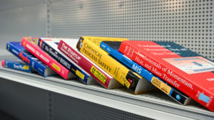 College textbooks stacked on a shelf in the Bookstore