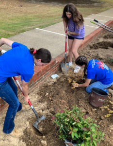 Students work in the flower beds at Woodard Hall. 
