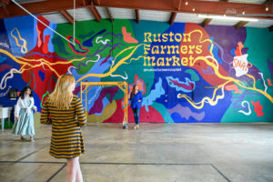Louisiana Tech University’s mural class poses with a newly painted mural at the Ruston Farmer’s Market with assistant professor Whitney Causey. Photo by Emerald McIntyre/Louisiana Tech University