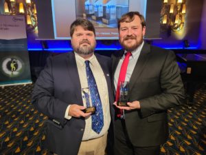 Dr. John Matthews and a male students stand together with awards in hand